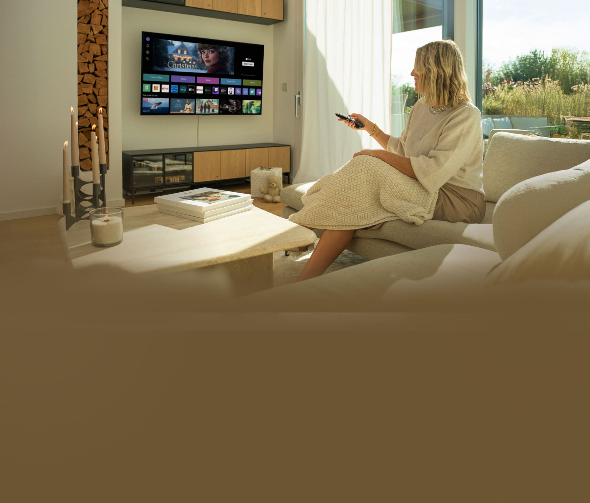 A woman relaxing on a sofa in a modern living room, using a remote to control the LG OLED G4 4K Smart TV. 