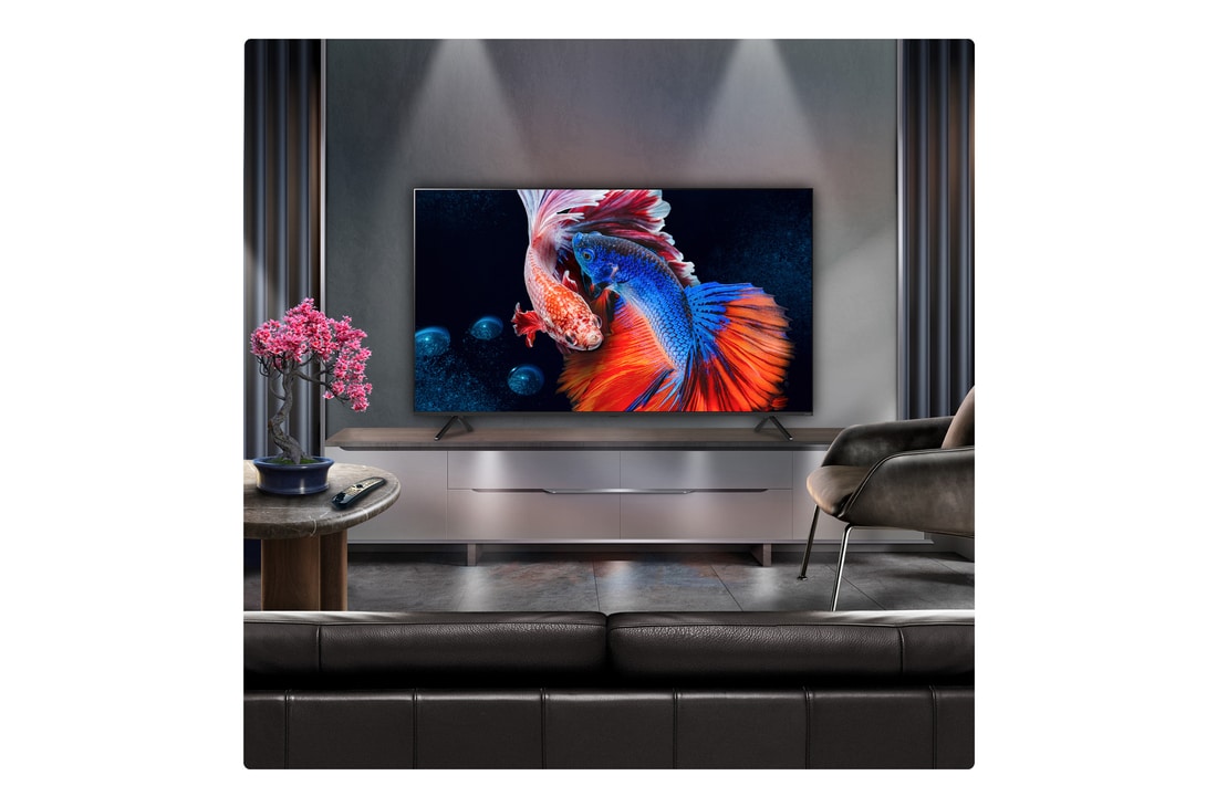 A family sits on a couch facing a LG QNED TV sitting above a TV stand with a little girl pointing to a screen depicting two dolphins. The title talks about how you can enjoy high resolution on a massive screen.