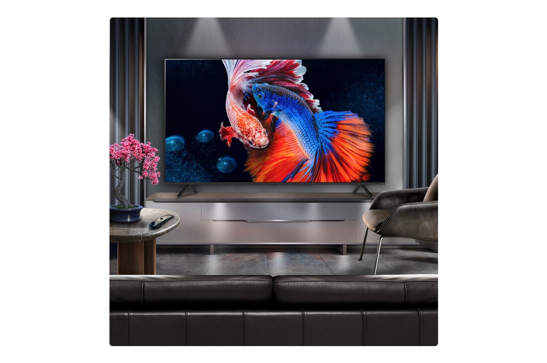 A family sits on a couch facing a LG QNED TV sitting above a TV stand with a little girl pointing to a screen depicting two dolphins. The title talks about how you can enjoy high resolution on a massive screen.