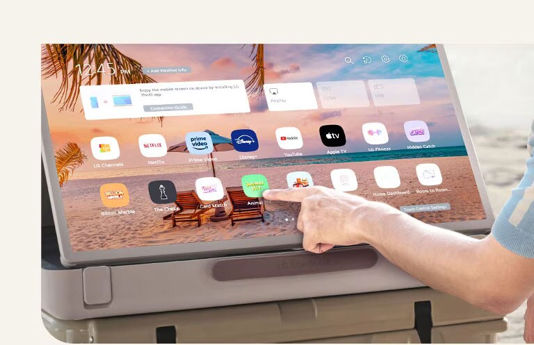 Close-up of LG StanbyME Go. The product is placed on a table, and the screen rotated horizontally. A hand is touching an icon.