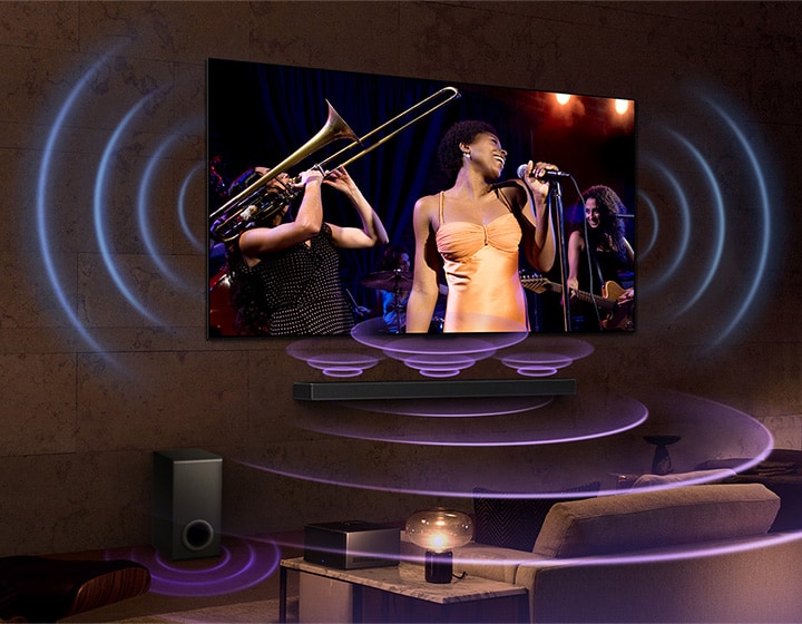 An image of an LG OLED TV in a room showing a music concert. Blue curved lines depicting TV sound and purple curved lines expressing Soundbar sound fill the space.