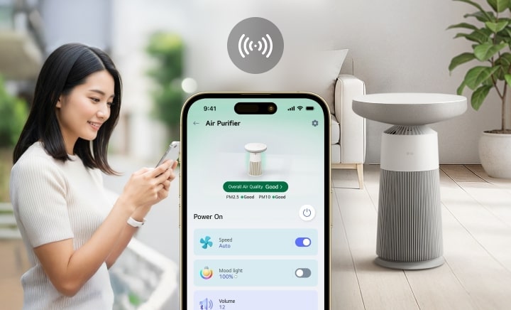 Người phụ nữ sử dụng ứng dụng điện thoại để điều khiển máy lọc không khí LG có đèn báo tâm trạng, được hiển thị bên cạnh màn hình điện thoại thông minh và máy lọc không khí trong phòng khách.