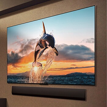 Wide view of a living room inside a premium home, a man is watching a movie on his wall-mounted LG OLED TV. The TV's design blends elegantly with the wall and the interior design.