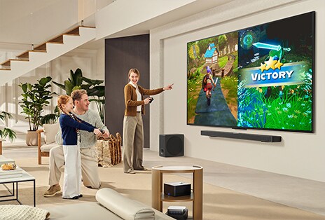 Gia đình ba người cùng nhau chơi game trong phòng khách, nơi TV LG treo tường trên loa thanh LG Soundbar. Zero Connect Box nằm bên trong bàn trà