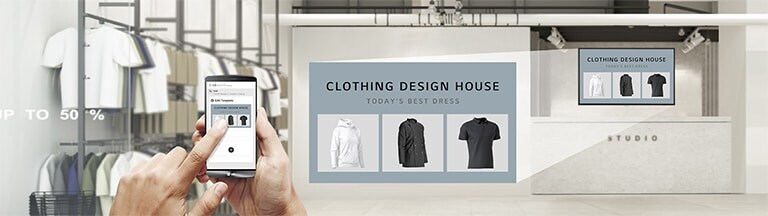Trong một cửa hàng quần áo, người dùng đang sử dụng ứng dụng để tạo nội dung quảng cáo để hiển thị trên UH5J-H được lắp trên tường của cửa hàng.