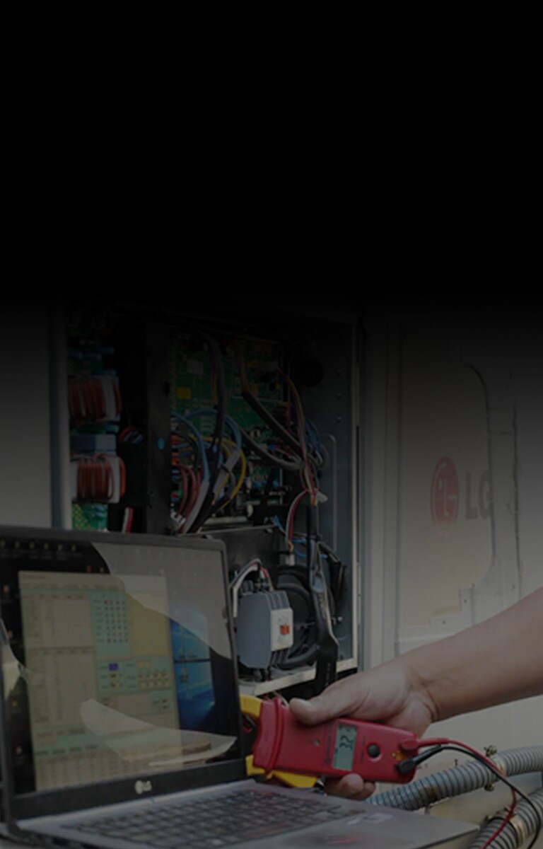 Một người đang sử dụng một công cụ hình chữ nhật màu đỏ được kết nối với máy tính xách tay, chẩn đoán một dàn nóng LG đang mở, hệ thống dây điện bên trong của nó lộ ra hoàn toàn.
