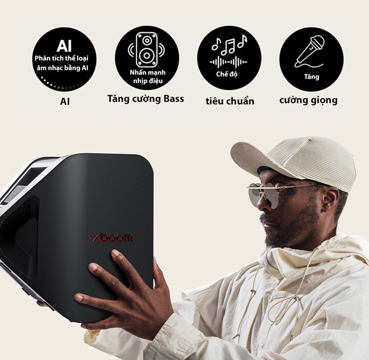 will.i.am in white outfit and white cap is holding xboom Stage 301 with his both arms to his face.