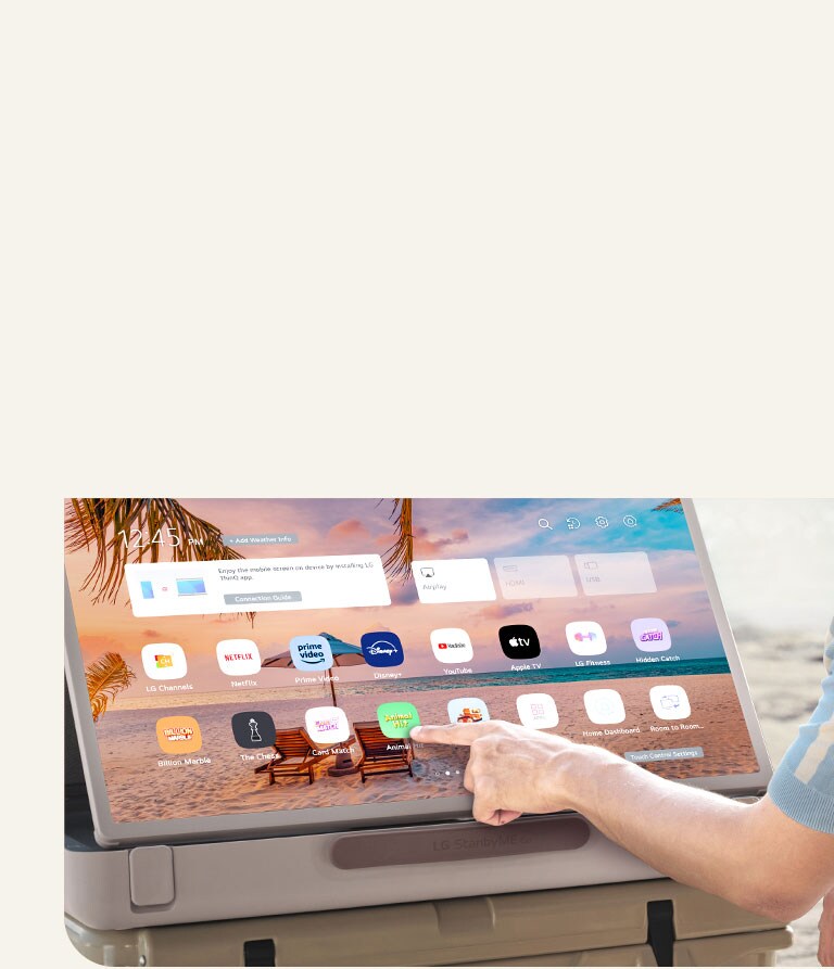 Cận cảnh LG StanbyME Go. Sản phẩm được đặt trên bàn, màn hình xoay ngang. Một bàn tay đang chạm vào một biểu tượng.