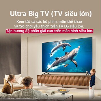 Cả gia đình ngồi trên chiếc ghế dài đối diện LG QNED TV nằm phía trên kệ TV, một cô bé chỉ vào màn hình đang chiếu cảnh hai chú cá heo. Tiêu đề nói về cách bạn trải nghiệm độ phân giải cao trên màn hình lớn.
