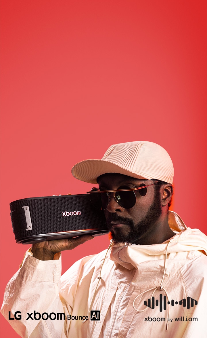 will.i.am diện đồ trắng và đeo kính râm, tay cầm xboom Bounce để sát mặt.