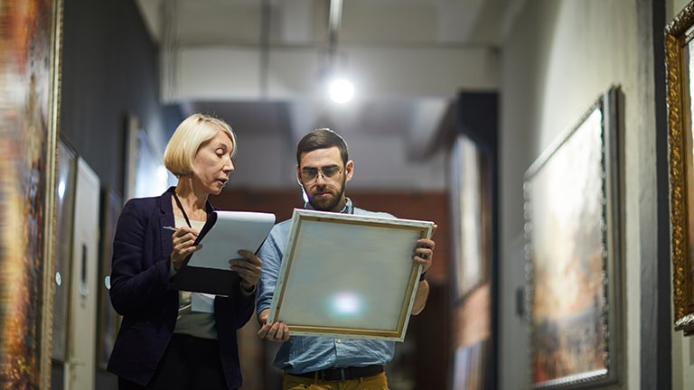 Image of two people looking at a drawing piece in a gallery.