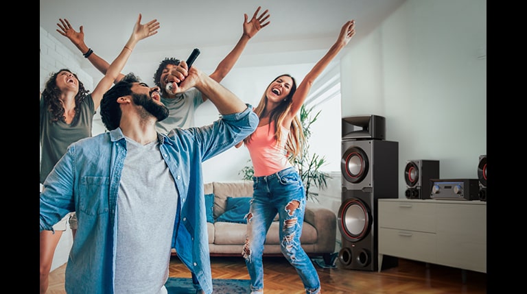 A group of people are enjoying karaoke in the living room, LG MR11 is placed beside them.