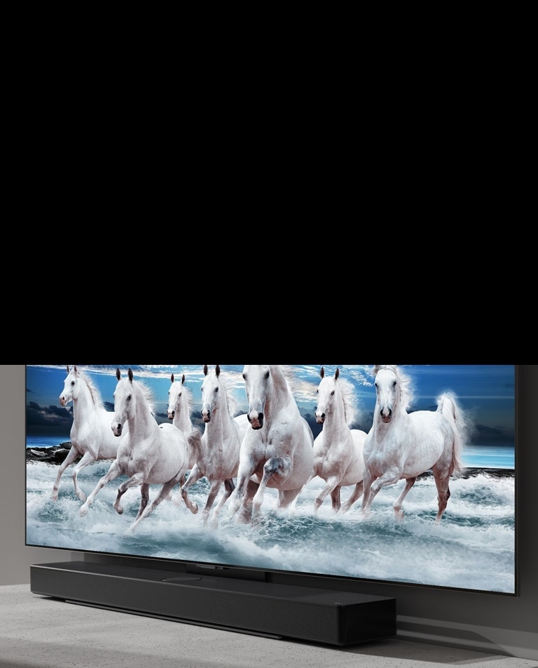 Soundbar  and TV are placed on the white table and 7 white horses are shown on the TV.