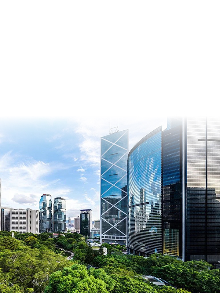 Panoramic view of a series of skyscrapers with reflective outer walls standing side by side next to a green park.