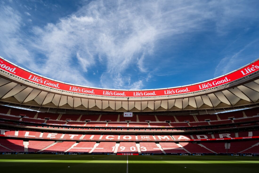 LG delivers a massive ribbon LED board installation at Atlético de Madrid’s football stadium, showcasing advanced mesh LED technology. The panoramic display wraps around the stands with vibrant “Life’s Good” branding under a clear blue sky.