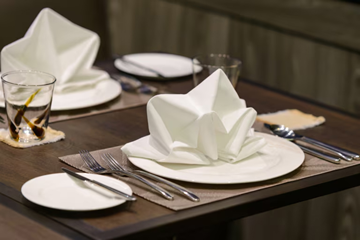 Restaurant table set with plates, glasses, and folded napkins