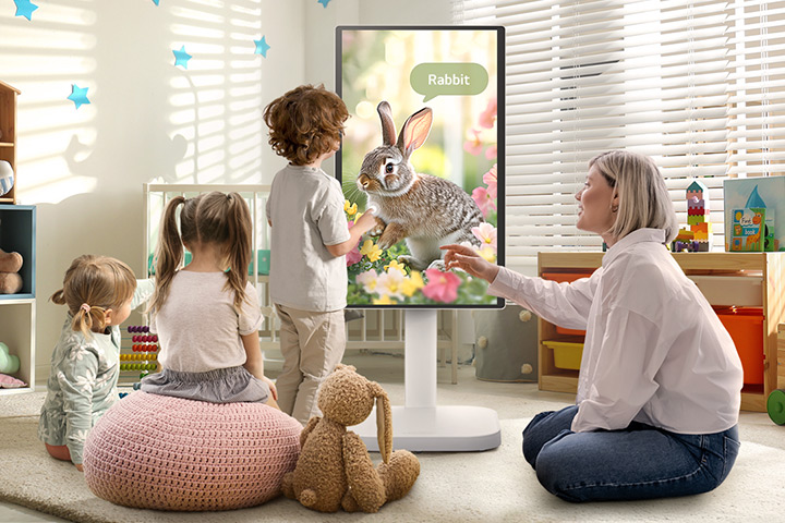 This picture shows a woman and three children playing using a LG Smart Monitor Swing.	