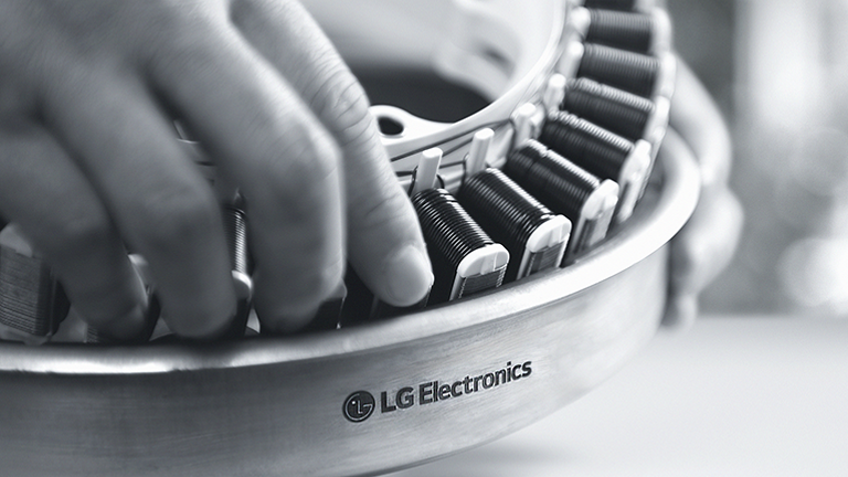 A close-up of a high-performance compressor with the LG Electronics logo, being assembled by hand. Emphasizing technical excellence and reliability.