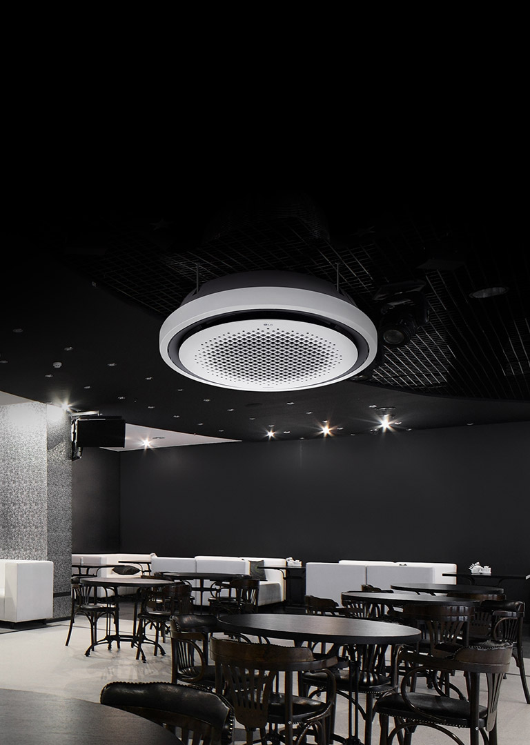 Black and white tone dining area with tables, chairs, and a sofa displayed. LG Round Cassette mounted on the ceiling.