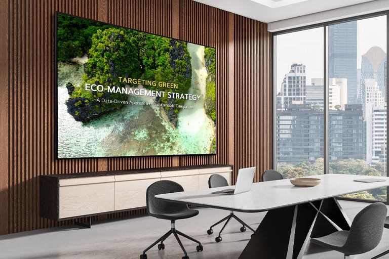 A signage display is mounted on the wall of a meeting room, clearly showing meeting content on the screen.