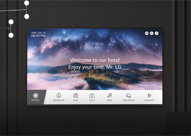 A wall in a dimly lit room features an LG TV, displaying a welcome message using the LG Pro:Centric Direct solution.