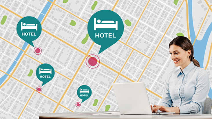 A woman sitting at the desk is using her laptop to manage hotel TVs across different locations.