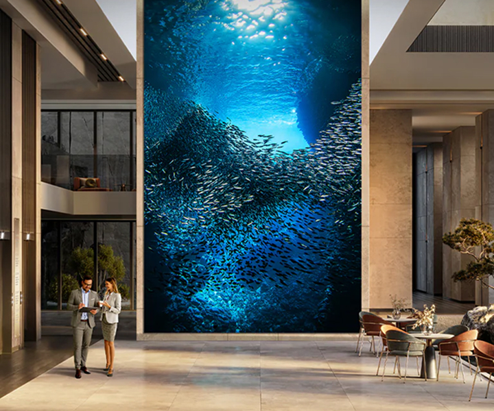 LG MAGNIT Micro LED display installed in a luxurious lobby, showcasing an immersive underwater scene with a school of fish, delivering stunning visual impact and premium viewing experience.