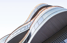 Modern glass building with curved architectural design viewed from below.