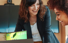 A teacher and a student smiling while working together on a laptop.