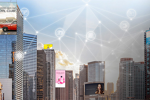 City skyline with tall buildings featuring large digital billboards. Overlay graphics show interconnected network icons, symbolizing smart city connectivity and digital communication