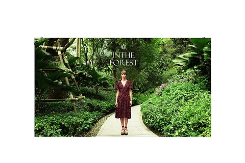 Indoor LED display showing a woman walking on a garden path surrounded by lush greenery, presented against a plain light background.