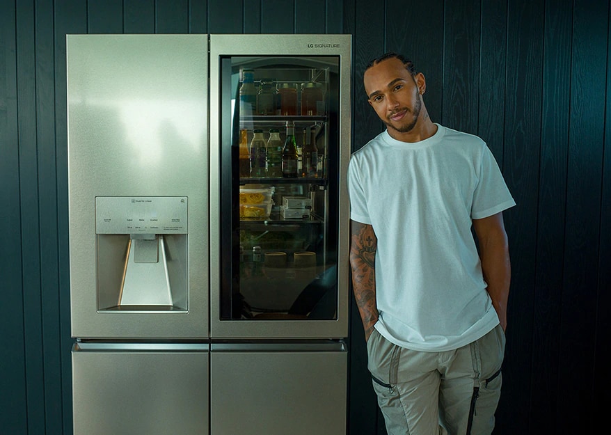 Lewis Hamilton leaning against the LG SIGNATURE Refrigerator.