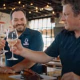 Thumbnail showing two men toasting with glasses of white wine.