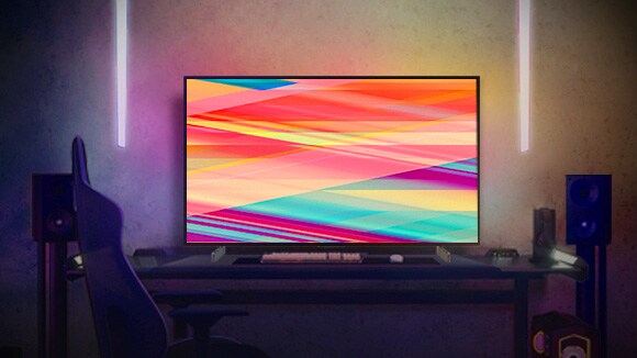 El LG OLED C2 está en una habitación con iluminación nocturna cálida, con sofás, muchos cojines, una lámpara, una mesita auxiliar y una planta