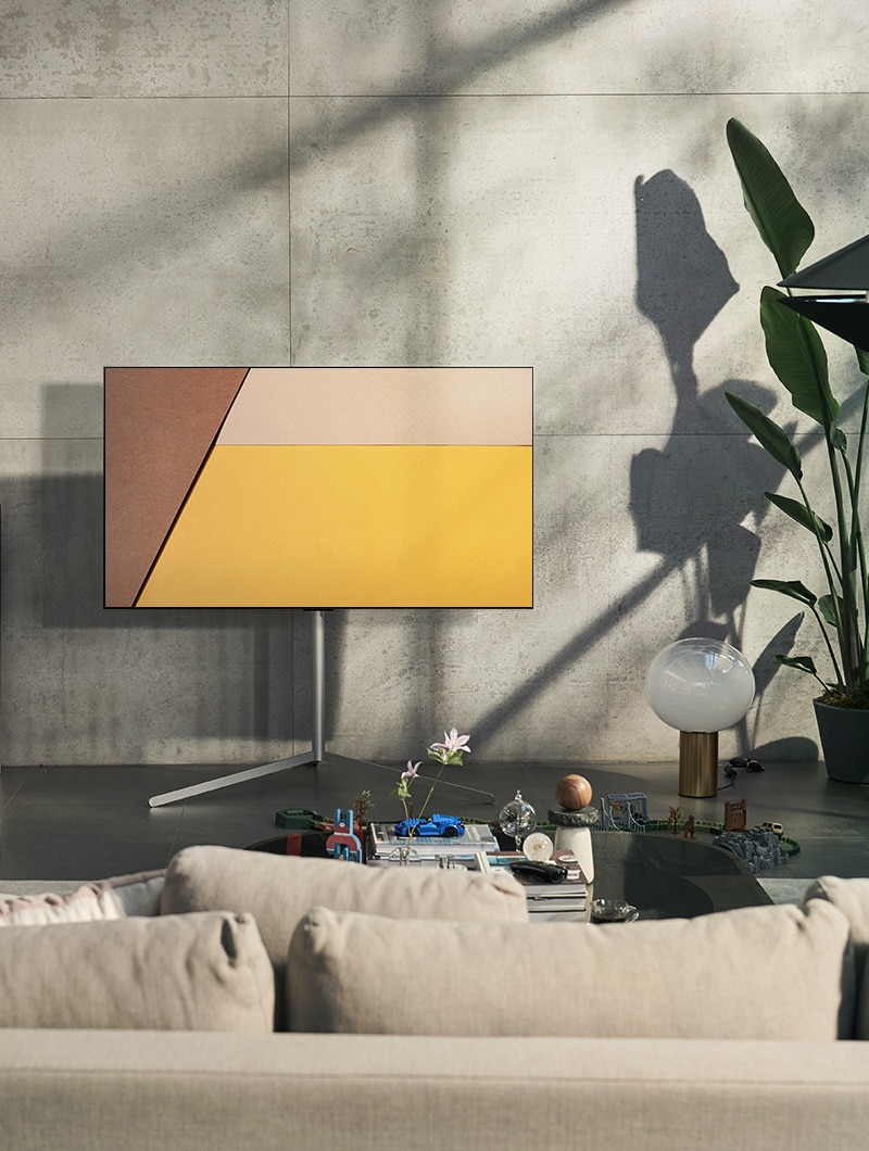En un moderno espacio gris frente a una ventana que muestra una piscina hay un televisor LG OLED. En un espacio neutral con ladrillos a la vista, detalles de madera y vegetación hay un televisor LG OLED.	