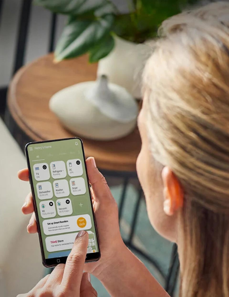A woman uses the LG ThinQ app on her smartphone