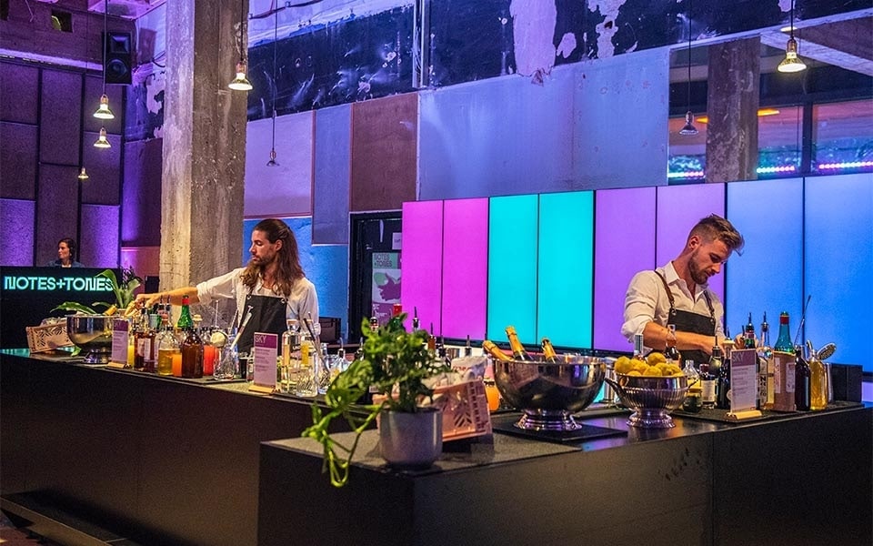 Two chefs prepare a meal in front of a wall of smart fridges