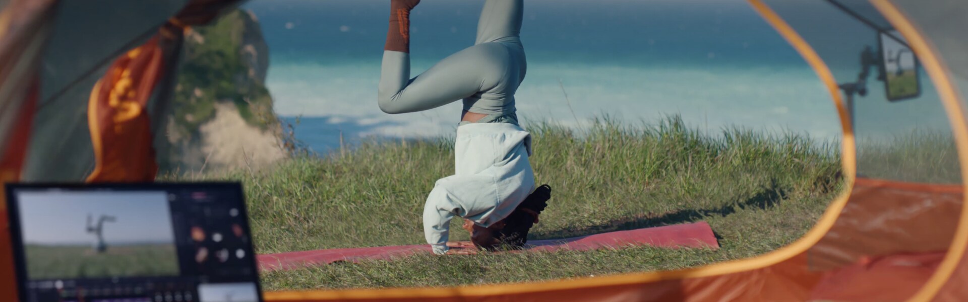 Eine Frau macht Kopfstände auf einer Yogamatte am Meer und filmt mit ihrem Smartphone, das auf einem LG Gram angezeigt wird.