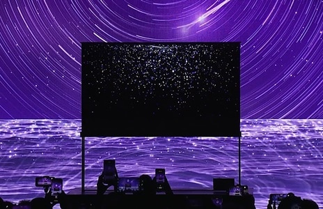 Behind the LG SIGNATURE OLED T, which shows starlight on the background screen, there is a sea, moon, and stars shining in purple as the background.