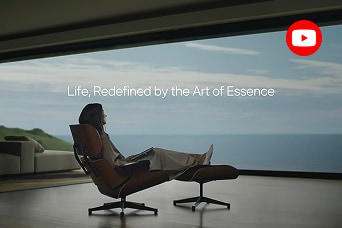 A woman sitting on a chair is looking at a scene overlooking the sea.