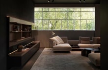 Couches and side tables are arranged in the living room with a long window across the whole wall.