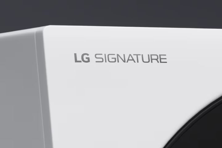 A close up image of the top left hand corner of the LG Signature Washing Machine, showing the top of the door and Quick Circle Display, and the LG Signature logo engraving.