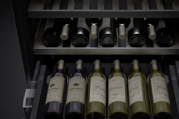 A close-up image of the inside of the wine cellar. Several bottles of wine are stored on the shelves, and the bottom shelf has been pulled out so that the wines can be easily viewed and accessed.