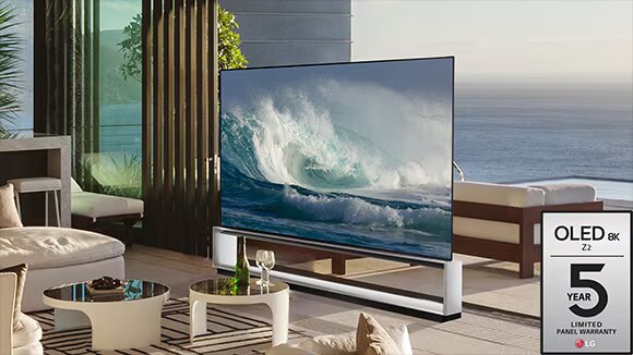 LG OLED Z2 is in a minimalist white room in front of a window that looks onto a forest of trees