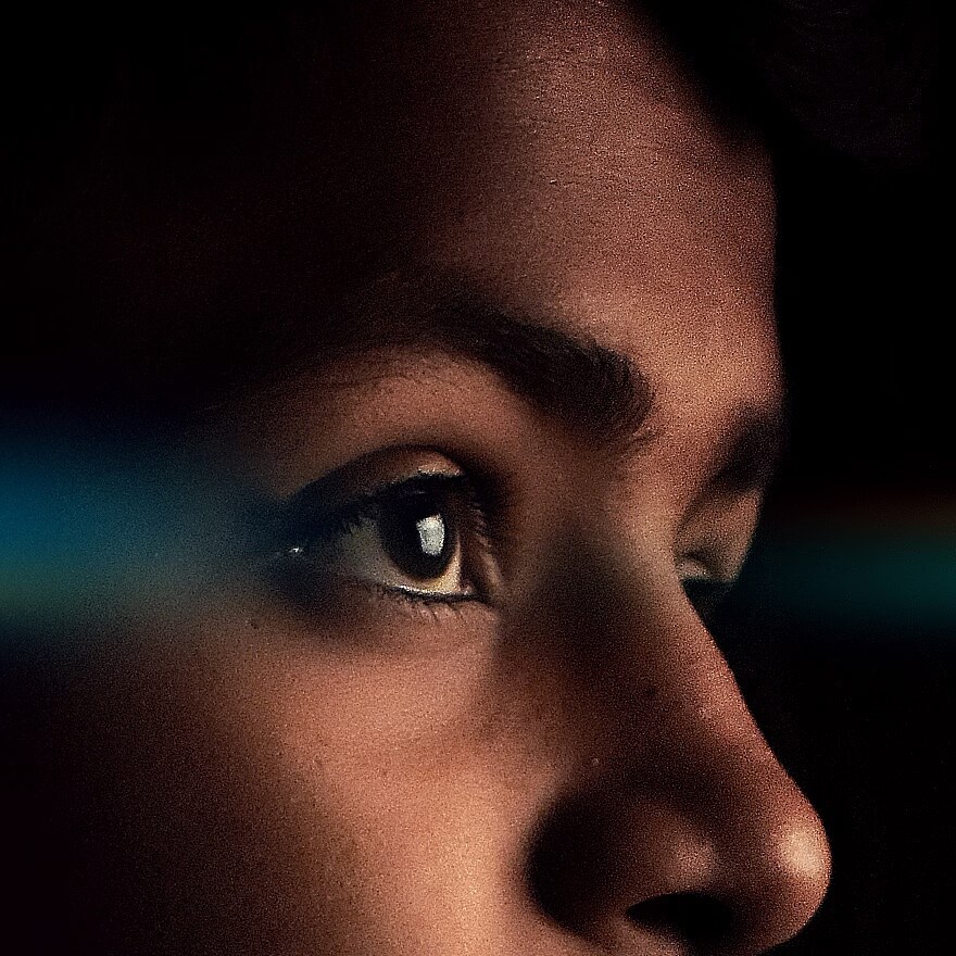 A side closeup view of a child looking towards a television that is not in the frame