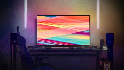 夜間,LG OLED C2 位於燈光柔和的房間內,房內有梳化、很多靠墊、一盞燈、一張茶几和一棵盆栽