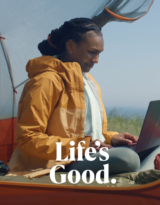 A woman in a yellow jacket using an LG gram outdoors, looking relaxed and focused.