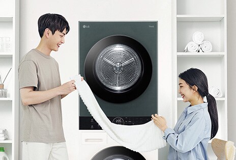 ชายหญิงกำลังพับผ้าหน้าเครื่องซักผ้า LG พร้อมชั้นวางของและข้อมูลสมัครรับโปรโมชั่น ข่าวสาร และการอัปเดตผลิตภัณฑ์ LG.