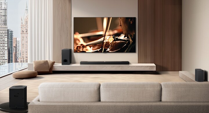 LG Soundbar, LG TV, ein Subwoofer und hintere Lautsprecher stehen in einer modernen Stadtwohnung. Der Hintergrund wird gedimmt und ein Raster wird über das Bild des LG TVs gelegt, wie ein Scan des Raums. Eine gepunktete Linie geht von einem der hinteren Lautsprecher aus, um die lineare Anordnung der beiden hinteren Lautsprecher zu zeigen. Aus der Frontalperspektive der hinteren Lautsprecher kommen aus Tröpfchen bestehende weiße Schallwellen.