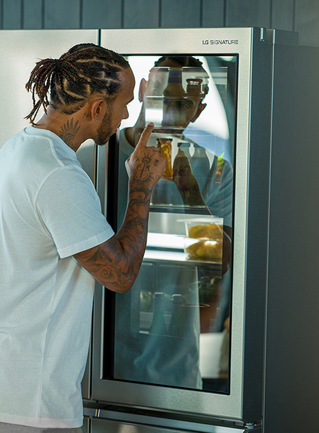 Lewis Hamilton touching the LG SIGNATURE Refrigerator instaview.